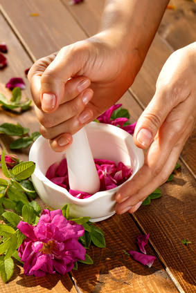 A pair of female hands holding a  mortar grinding rose petals